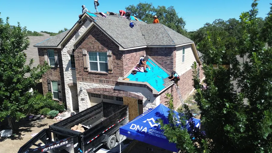 DNA job site setup on a brick two-story home by DNA Restoration & Construction
