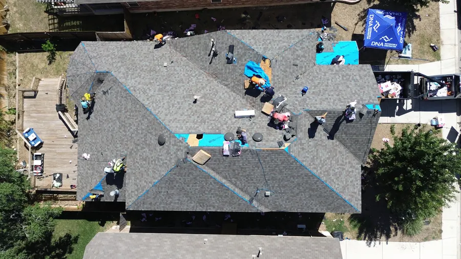 Crew installing new architectural shingles by DNA Restoration & Construction