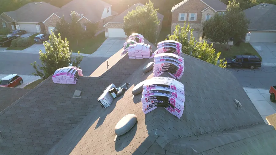 Close-up drone photo of new shingle bundles staged on the roof ridge