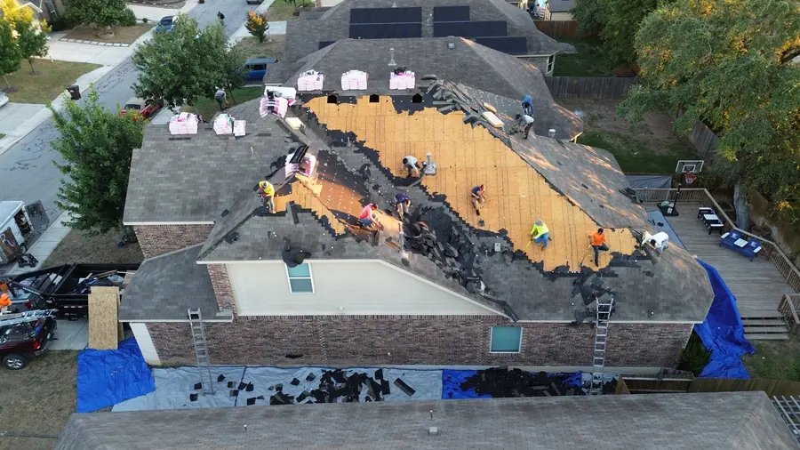 Drone photo of a DNA crew tearing off an old roof with tarps protecting the yard